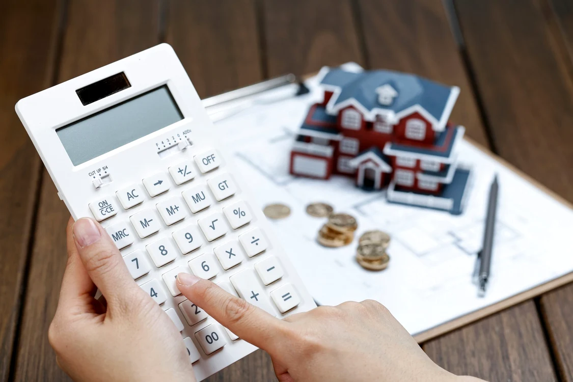 female hand operating calculator front villa house model 1 scaled jpg