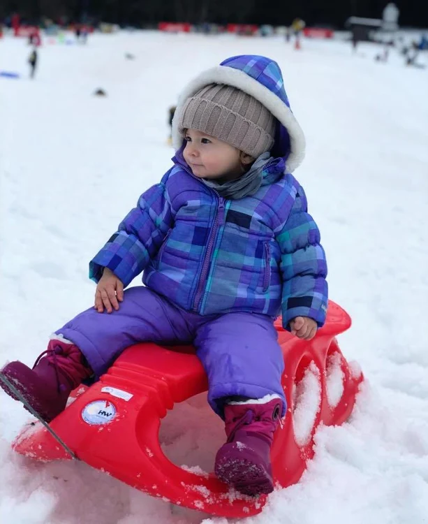 Anastasia, fiica cea mică a lui Liviu Vârciu, pe săniuță, în Poiana Brașov