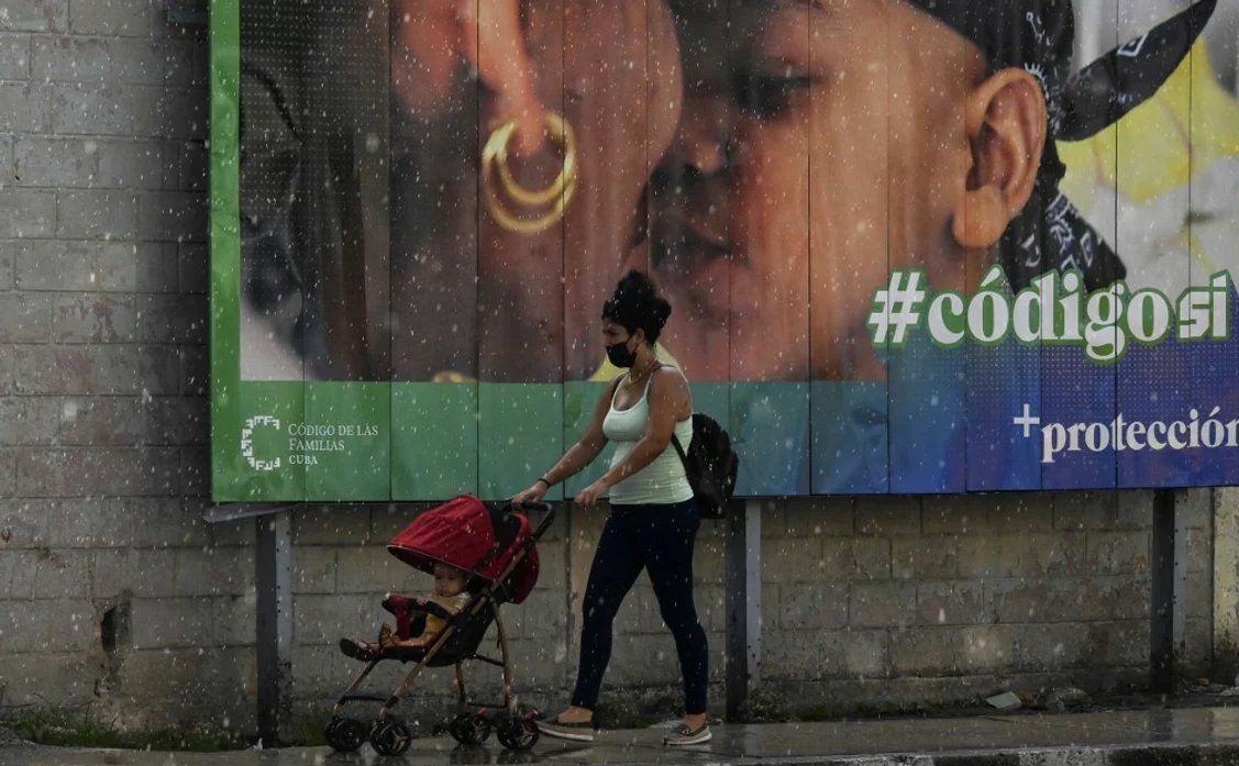 O mamă trece cu copilul prin fața unui afiș de susținere a noului cod al familiei | Foto AFP
