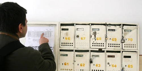 Un sucevean analizează cu atenţie lista la întreţinere de pe afişierul din holul blocului în care locuieşte