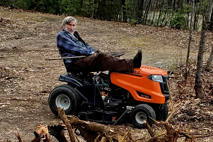 Milionarul Goeffrey Holt într-un parc, alături de mașina de tuns iarba