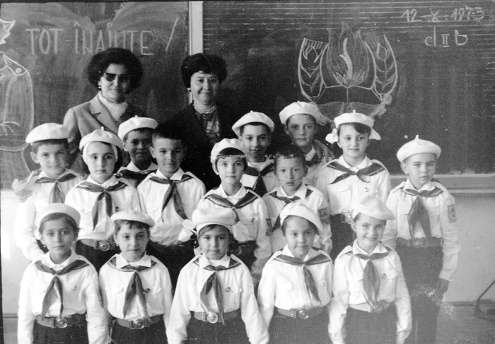 Grup de pionieri, alături de învățătoare, în fața tablei, îmbrăcați în uniforme