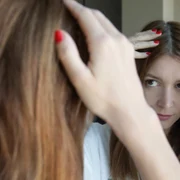 Femeie care își verifică firele albe de păr în oglindă FOTO Shutterstock 