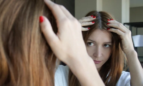 Femeie care își verifică firele albe de păr în oglindă FOTO Shutterstock 