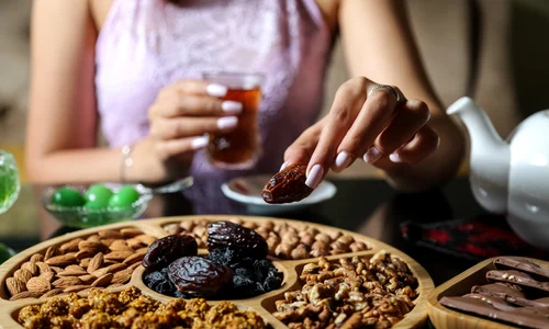 top view woman eating dry persimmon with tea mix nuts chocolate table jpg