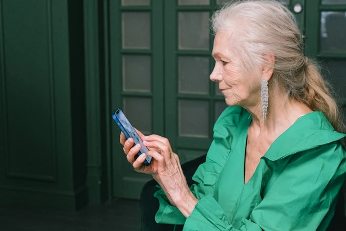 Femeie în vârstă care ține un telefon în mână
