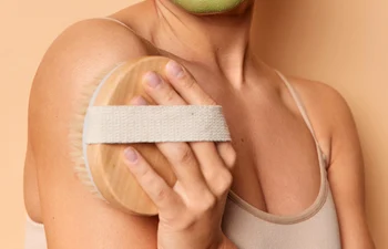 vertical shot positive woman enjoys beauty treatments wears green mask made natural ingredients makes anti cellulite massage with bath brush stands bare shoulders indoor body care concept jpg