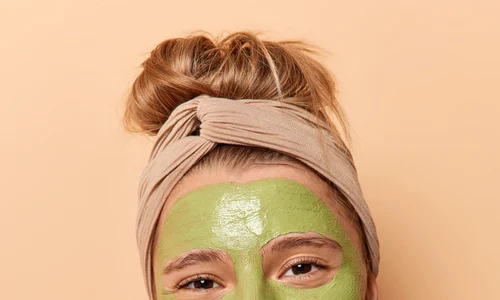 vertical shot positive woman enjoys beauty treatments wears green mask made natural ingredients makes anti cellulite massage with bath brush stands bare shoulders indoor body care concept jpg