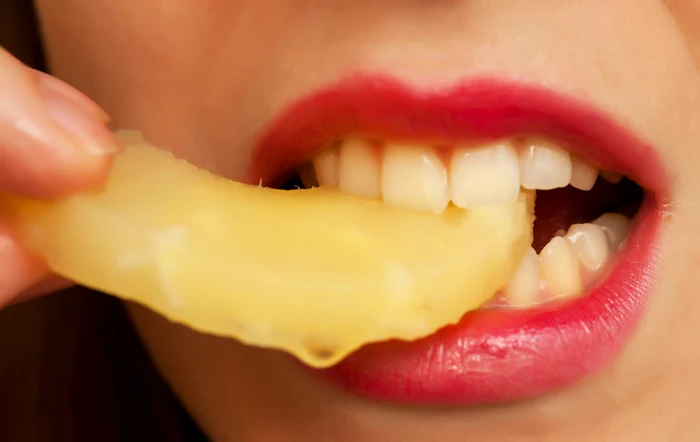 Fată mâncand o bucată de ananas