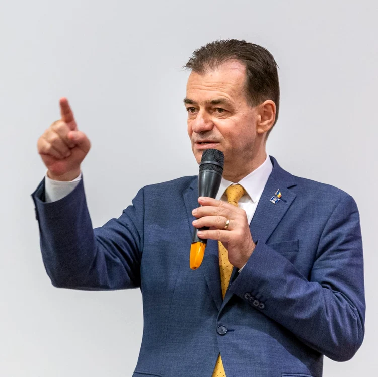 Ludovic Orban la costum si cravata vorbind la microfon si gesticuland cu mana dreapta