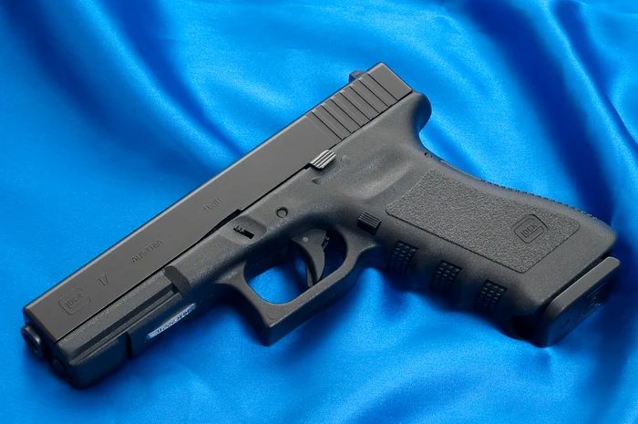 pistol Glock expus pe fundal albastru