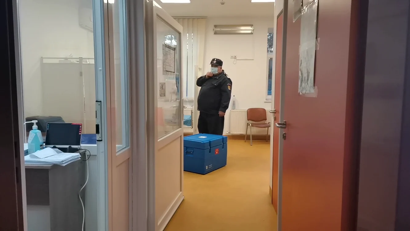 Un angajat al MAI supraveghează cutia cu vaccinuri, în Centrul de Vaccinare Rădăuţi FOTO: Oana Şlemco