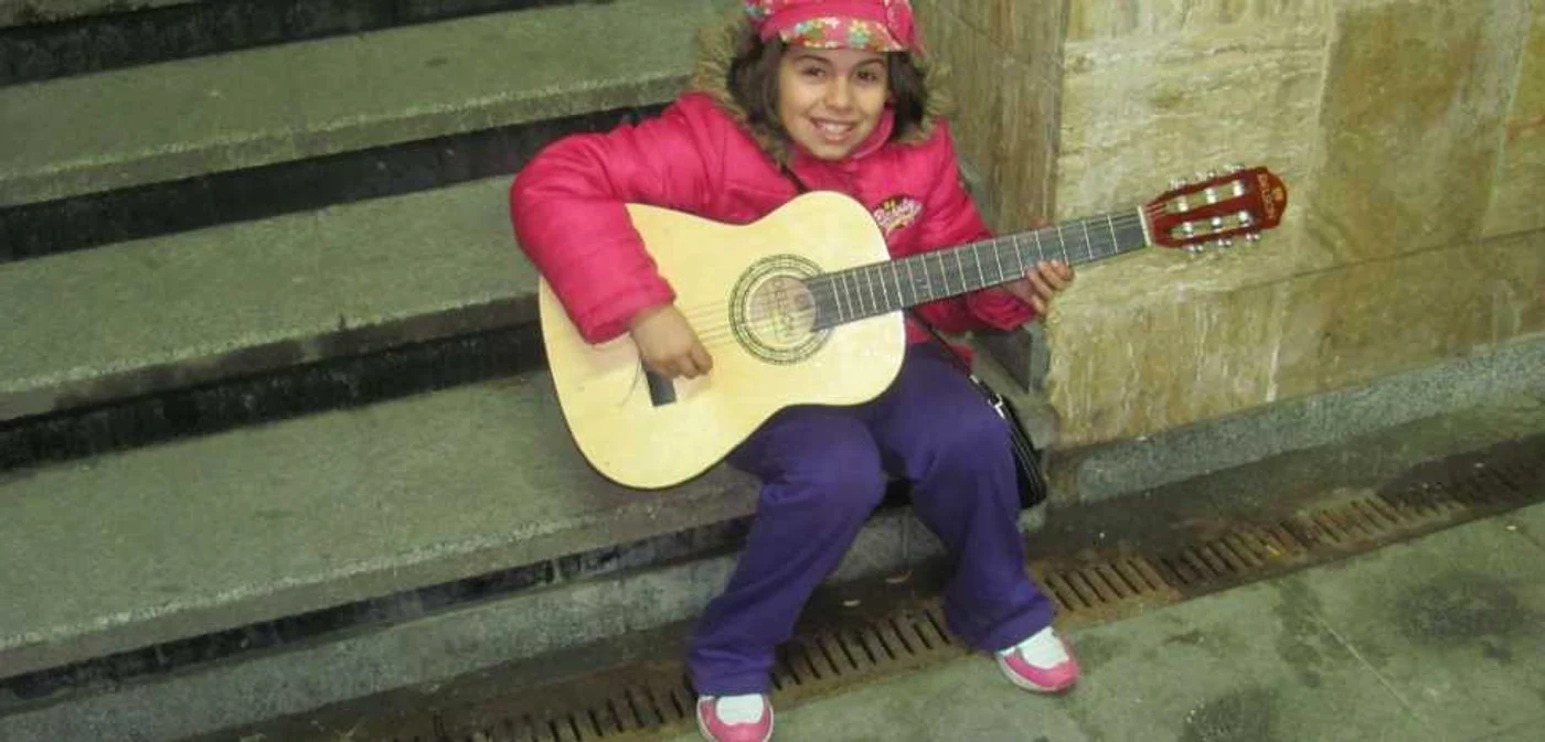 Sorana Olariu, cantand la chitara, cu o cutie pentru bani in fata, intr-un pasaj din centrul Sibiului - Foto Ramona Găină