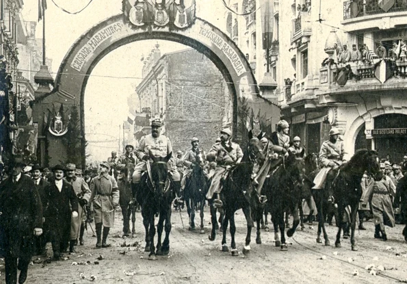 Foto sus: Trecerea familiei regale și a generalului Berthelot pe sub Arcul de Triumf ridicat pe Calea Victoriei, la intrarea în Piața Palatului Regal, la 18 Noiembrie/1 Decembrie 1918 (© Colecția Muzeului Militar Naţional „Regele Ferdinand I”)