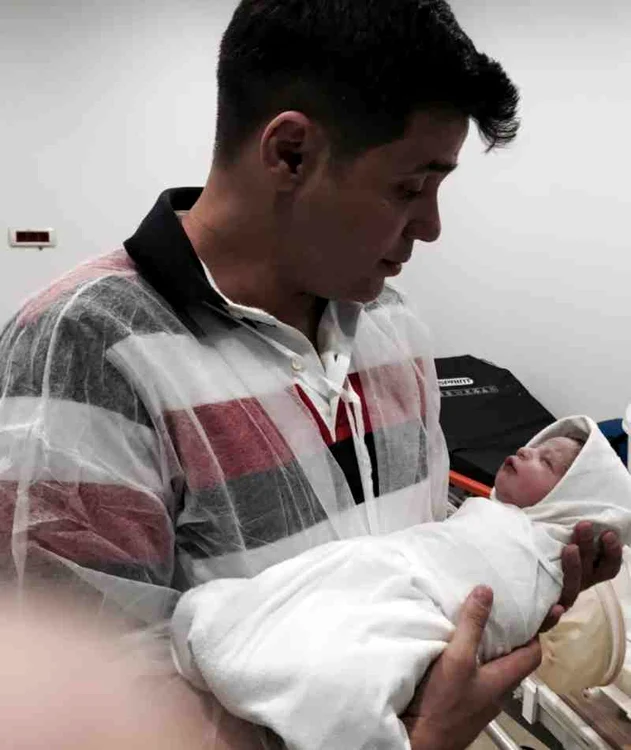 Cove îşi ţine copilul în braţe cu grijă şi cu mândrie