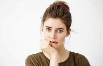 beautiful shy young woman with hair bun thinking biting lip jpg