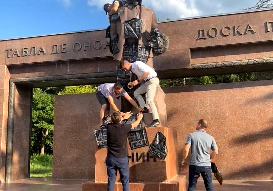 Valeriu Munteanu, Vlad Bileţchi şi Dorin Chirtoacă în momentul în care lipeau pungi pe monumentul lui Vladimir Lenin din Chişinău