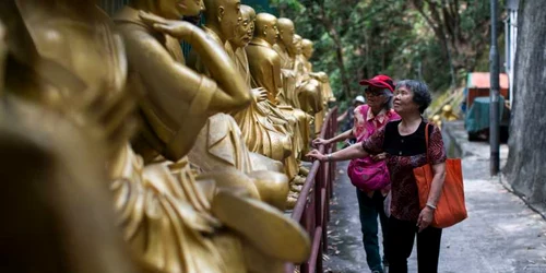 Două femei în vârstă privesc statuile de aur ale lui Buddha în drum spre Manastirea Ten Thousand Buddhas în timpul sărbătorilor de ziua lui Buddha în Shatin Hong Kong China FOTO EPA / Jerome Favre