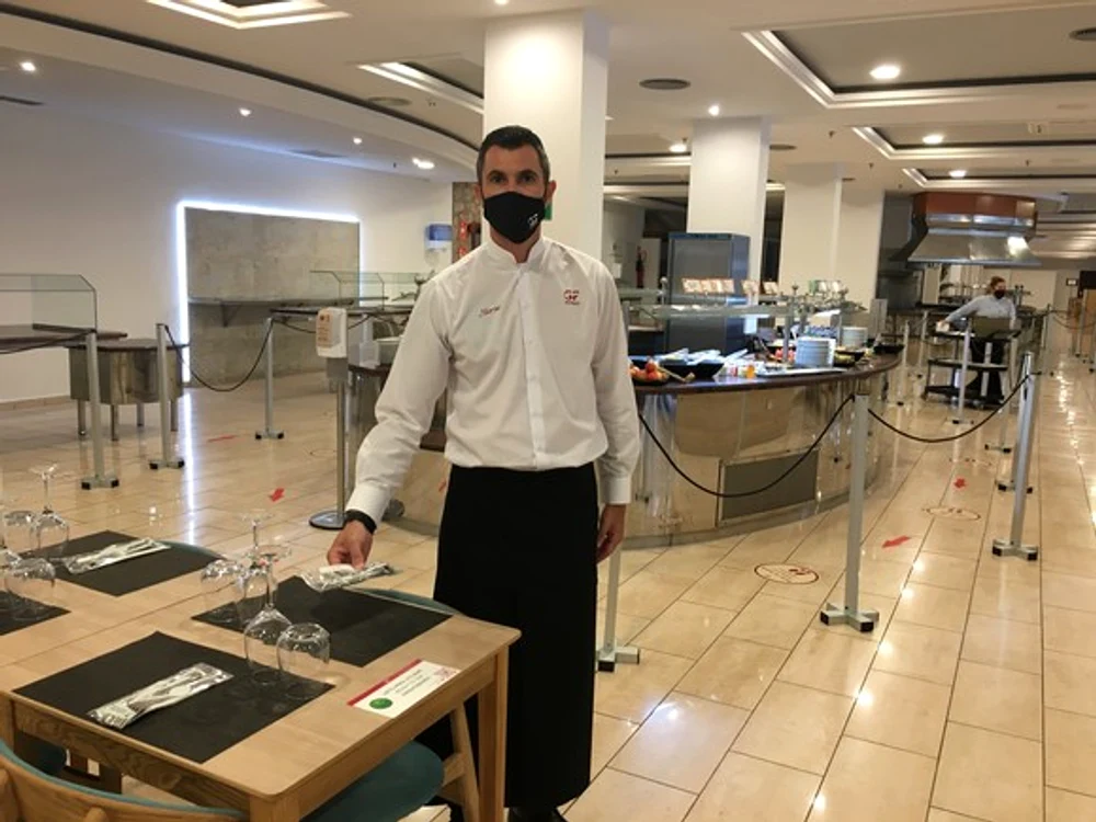 
    Marius, un chelner român, pune la masă tacâmuri sigilate   