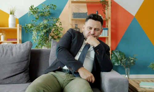 barbat sta inconfortabil pe canapea hemoroizi Zpp6LW9mMbg jpg