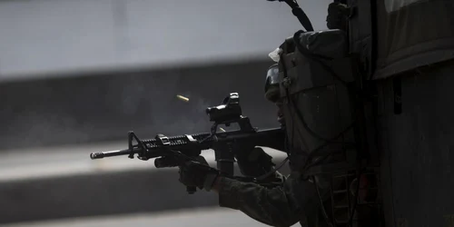 Un soldat brazilian trage în timpul unui conflict cu traficanţii de droguri  la intrarea din mahalua Vila do Joao în Rio de Janeiro Brazilia FOTO AP