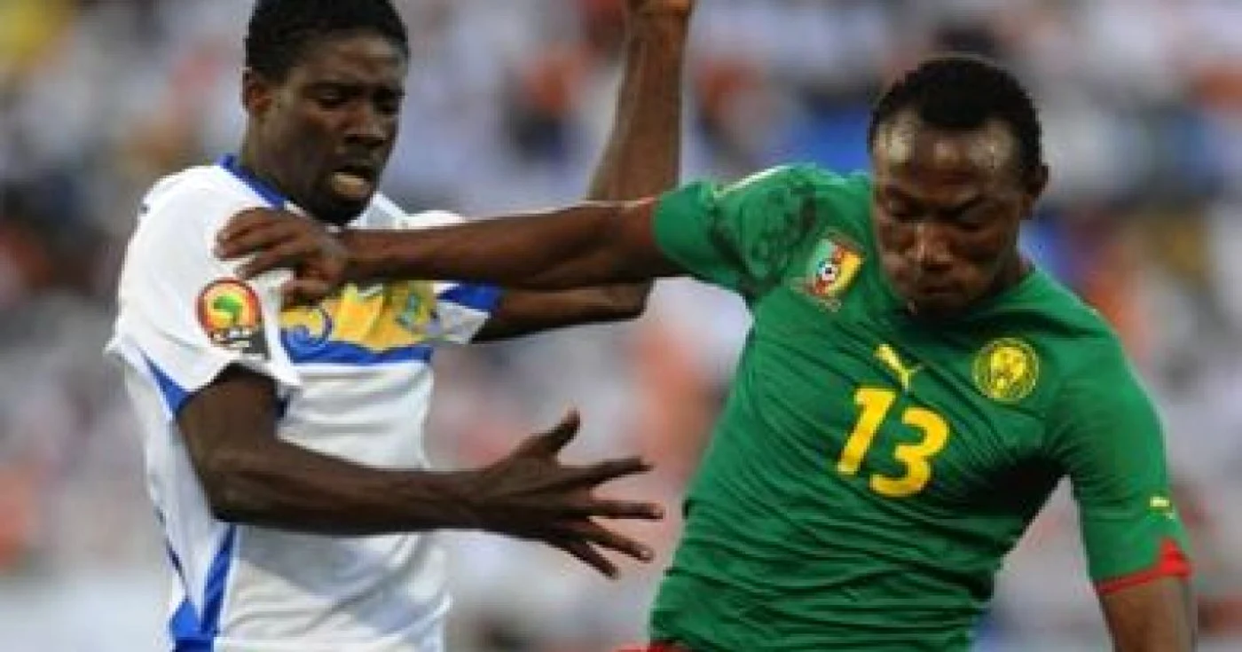 Georges Ambourouet, în echipament alb, în duel cu un camerunez la Cupa Africii 