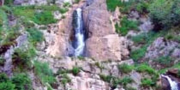 Apa se scurge din pântecul muntelui peste cele trei trepte stâncoase 