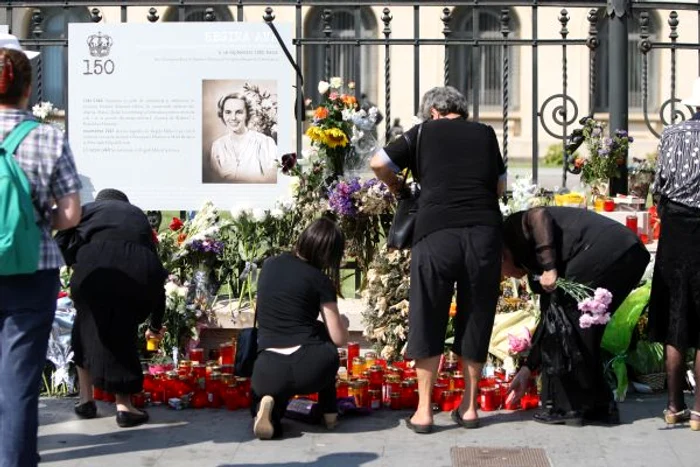 Zeci de oameni au venit să aprindă lumânări şi au depus flori pe trotuarul din faţa Palatului Regal.