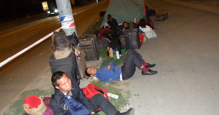 Muncitorii stau lângă şantier şi dorm pe trotuar