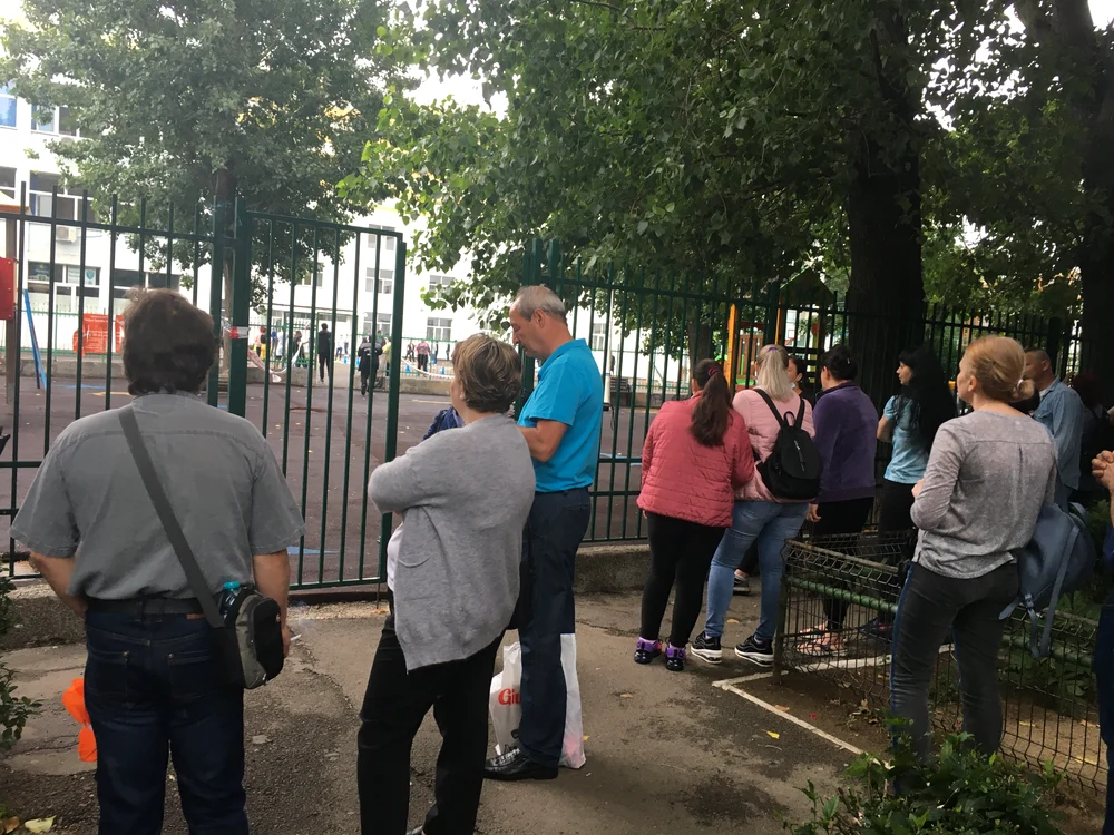 Părinții așteaptă de partea cealaltă a gardului