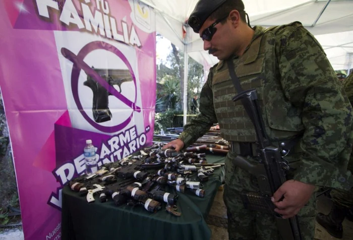 Un soldat al Armatei Mexicane verifică armele predate în schimbul banilor într-un proiect iniţiat de conducătorii din Mexico City FOTO AFP