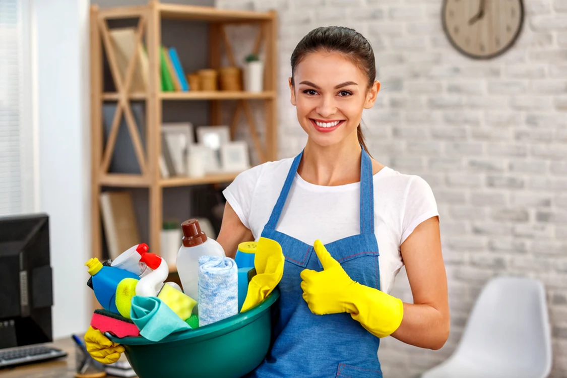 Femeie pregătită să facă curățenie echipată cu un kit de produse într-un lighean Foto HomeMaidBetter