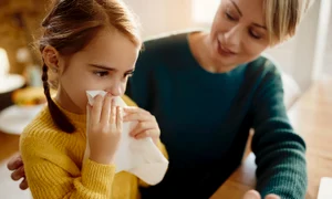little girl blowing nose while being with her mother home jpg