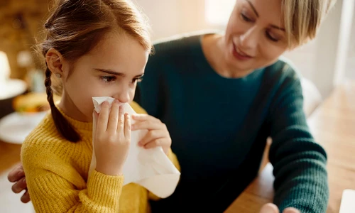 little girl blowing nose while being with her mother home jpg