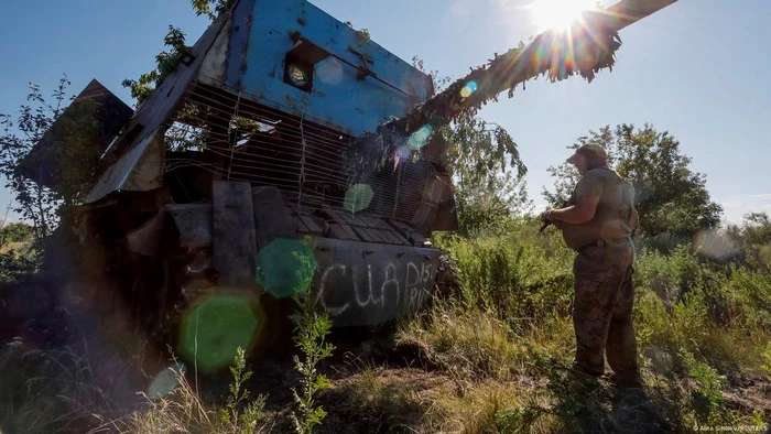 Un soldat ucrainean inspectează un tanc rusesc T-62 distrus