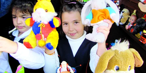 Denisa Meşter (centru) ţine la înălţime jucăriile colorate pe care le vinde cu cinci lei bucata