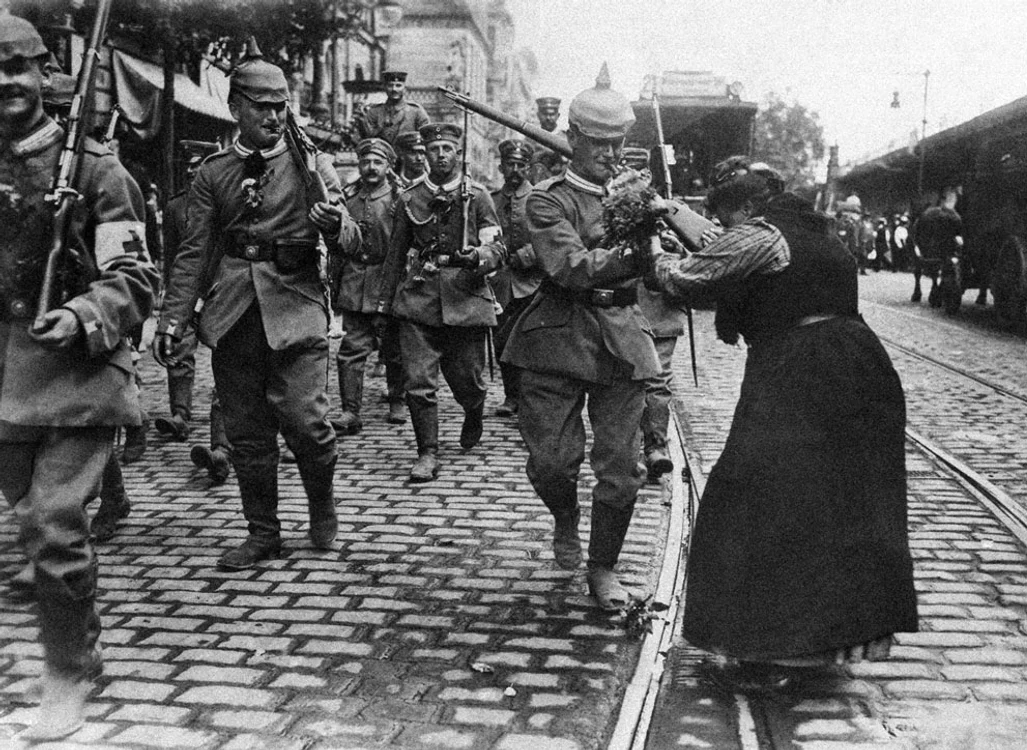 La puţin timp după asasinarea Arhiducelui,  Austro-Ungaria a dat un ultimatum Serbiei,  cerând să oprească toate activităţile împotriva sa,  să dizolve anumite grupări politice,  să înlăture anumiţi politicieni şi să îi aresteze pe aceia care complotaseră la comiterea asasinatului. Totul în 48 de ore. Serbia,  susţinută de vechiul său aliat,  Rusia,  a refuzat politicos să se supună pe deplin cerinţelor şi a început mobilizarea armatei. La scurt timp,  Austro-Ungaria,  sprijinită de Germania,  a declarat război Serbiei,  pe 28 iulie 1914. Atunci o întreagă reţea de tratate s-a activat,  iar într-o lună,  Germania,  Austro-Ungaria,  Rusia,  Franţa,  Marea Britanie şi Japonia îşi mobilizaseră armatele şi îşi declaraseră război. Război mondial,  care avea să devină total. În fotografie,  realizată în august 1914,  infanterişti prusaci,  îmbrăcaţi în noile uniforme de câmp gri,  părăsesc Berlinul şi se îndreaptă către linia frontului. Fetele îi întâmpină cu veselie şi flori. Drumul spre apocalipsă,  cu surle şi trâmbiţe...