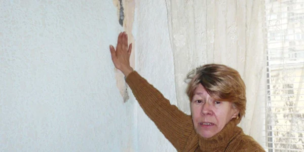 O locatară din bloc arată dezastrul făcut de igrasie