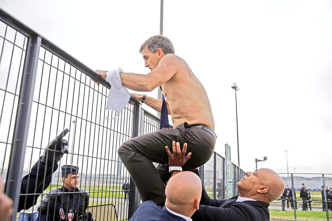 Directorul de Resurse Umane Xavier Broseta e împins de bodyguarzi peste gardFoto: AFP/AP