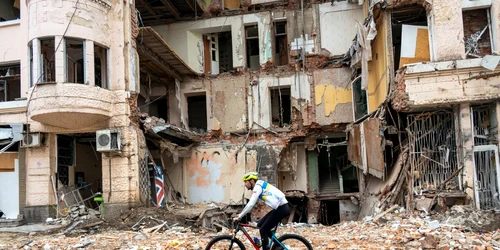 Un biciclist trece pe lângă o clădire distrusă de bombardamente în Harkov FOTO AFP