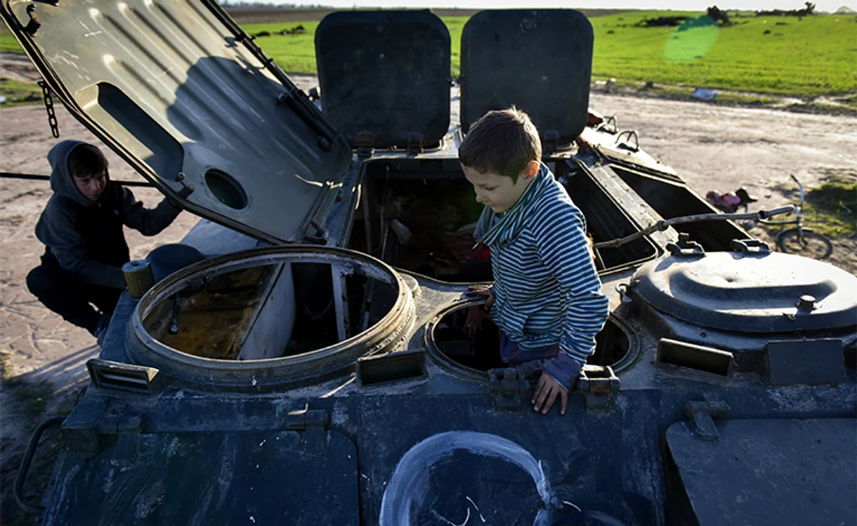 Fadei şi Bogdan din Lukaşivka se joacă de-a tanchiştii într-o epavă. Foto: EPA-EFE