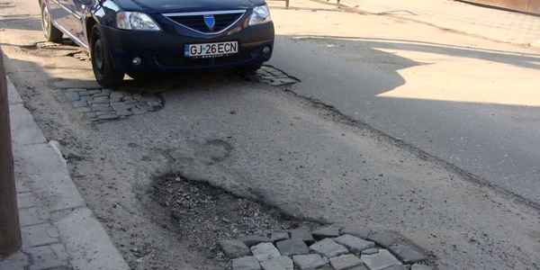 Gropile adânci de pe Strada Tudor Vladimirescu bagă maşinile în service