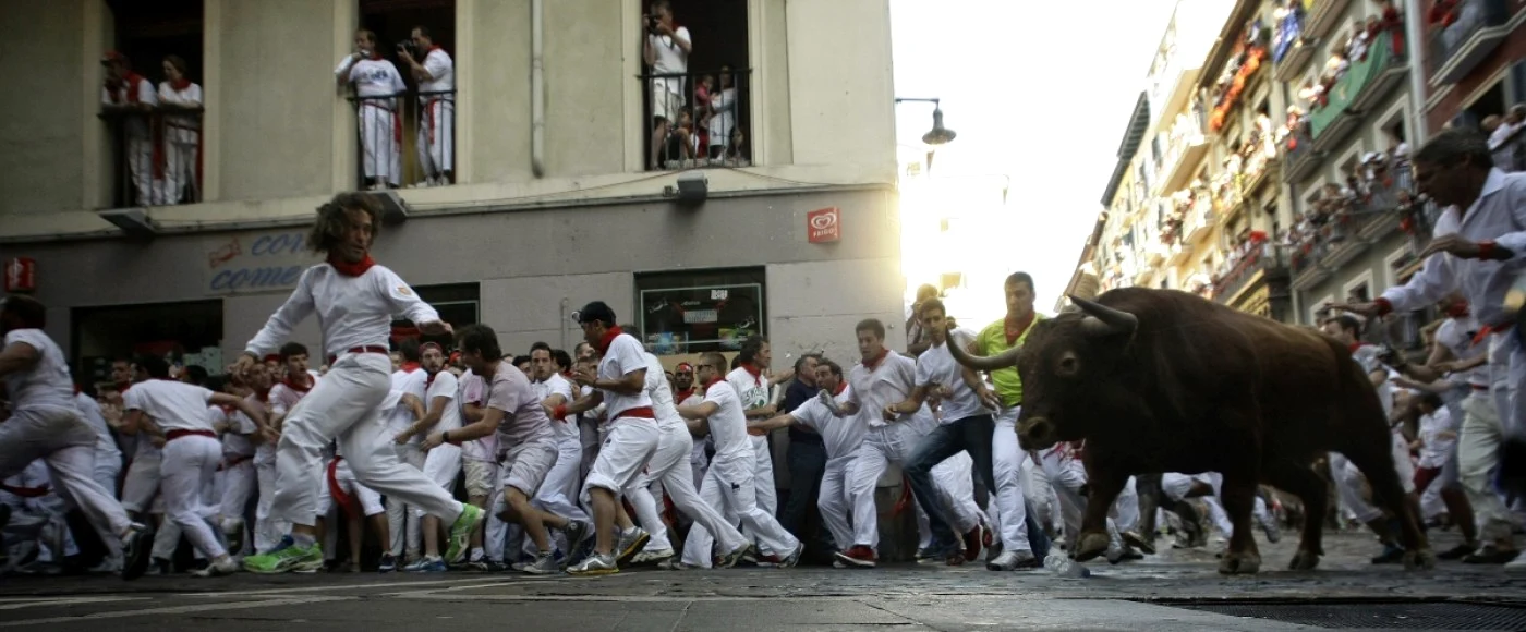 Un taur speriat e alergat de petrecăreţi, pe stradă în prima zi a festivalului San Fermin, de la Pamplona, Spania. FOTO Reuters