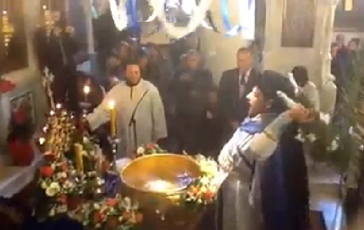 Preotul zelos le face baie cu aghiasmă credincioșilor din bisericăFoto: Captură video