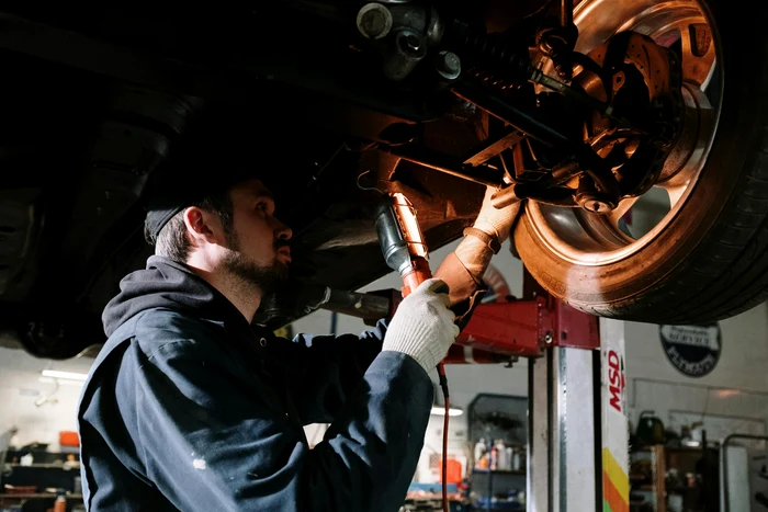 Un mecanic repară ceva la roata unei mașini