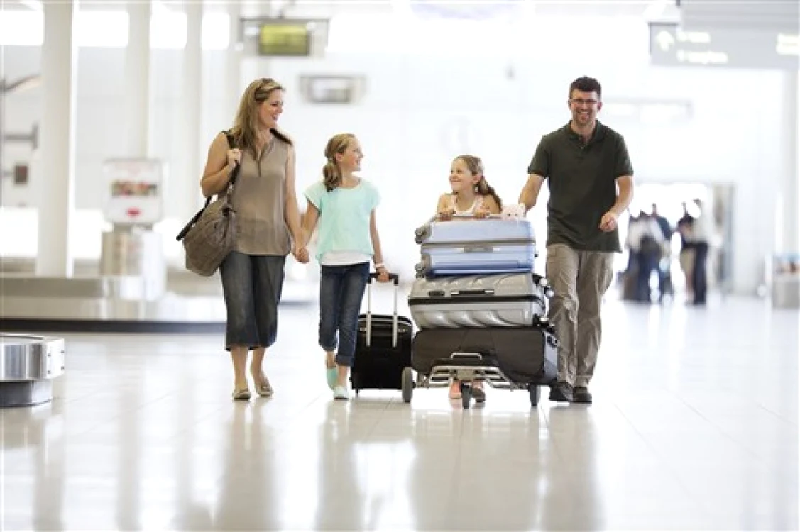 Familie cu doi copii și multe bagaje într-un aeroport
