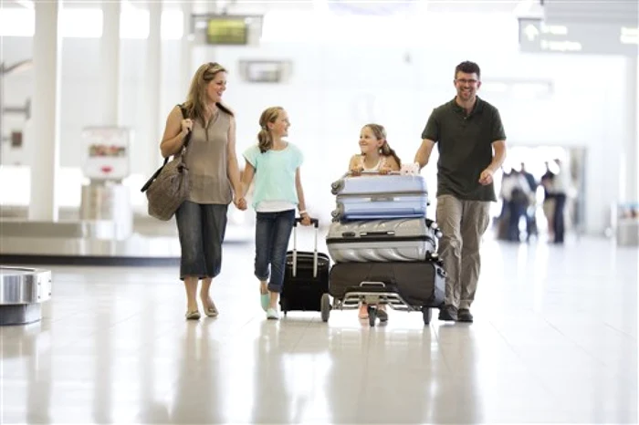 Familie cu doi copii și multe bagaje într-un aeroport