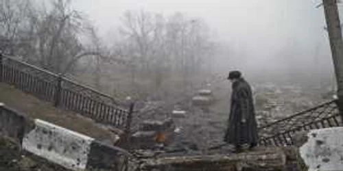 O bătrână traversează un pod distrus în timpul luptelor dintre ucraineni şi separatiştii proruşi din Doneţk
