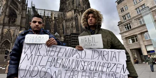Libanezul Mohamad (S) şi marocanul Nabil ţin un banner în faţa catedralei din Koln prin care cer scuze pentru comportamentul celorlalţi emigranţi în Koln Germania FOTO