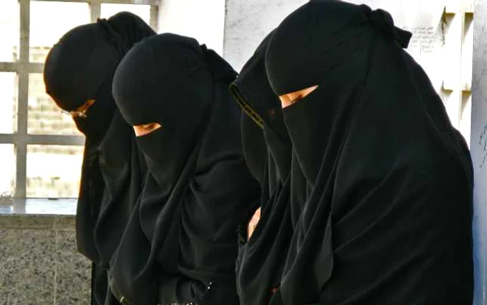 Patru femei din Afganistan, cu capul plecat, purtând hijab